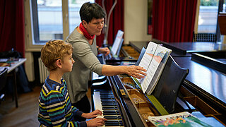 Kind am Klavier mit Lehrerin